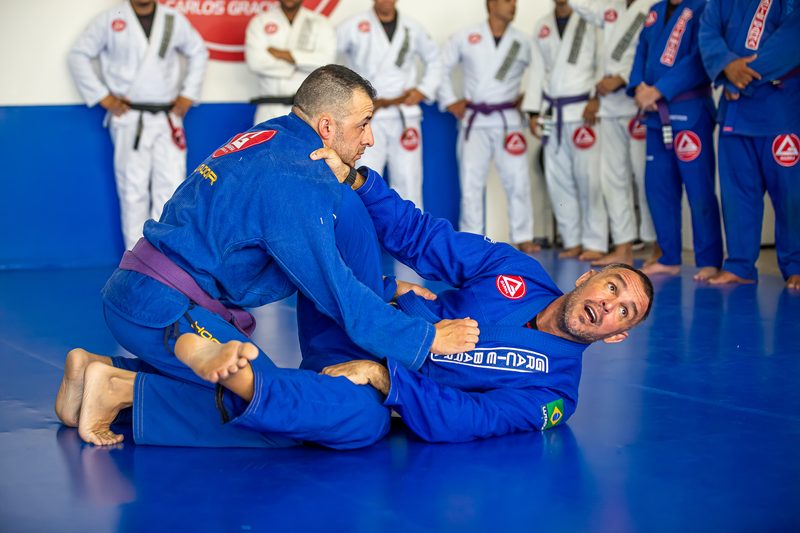 Instrutor demonstrando uma técnica no chão para a turma enfileirada