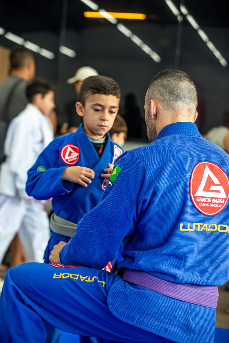 Instrutor ajustando o kimono de um aluno da turma kids